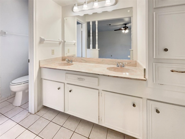 full bath with toilet, double vanity, a sink, and tile patterned floors