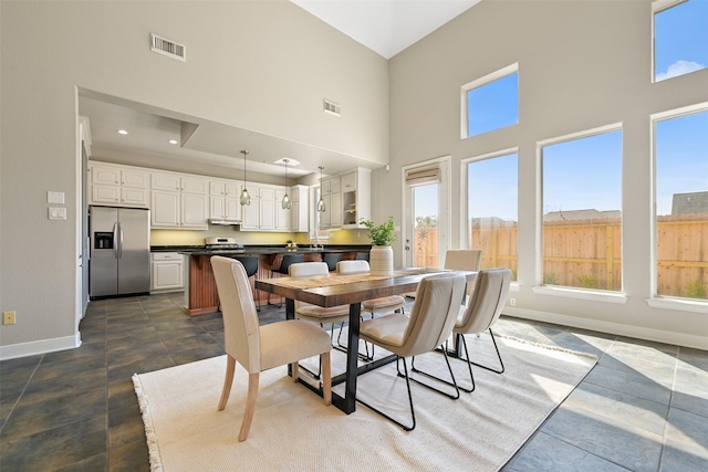 dining space featuring recessed lighting, visible vents, baseboards, and a high ceiling