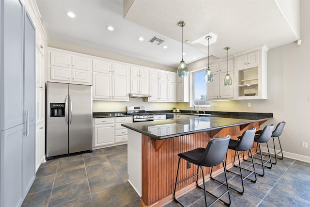 kitchen with dark countertops, white cabinets, visible vents, and stainless steel appliances