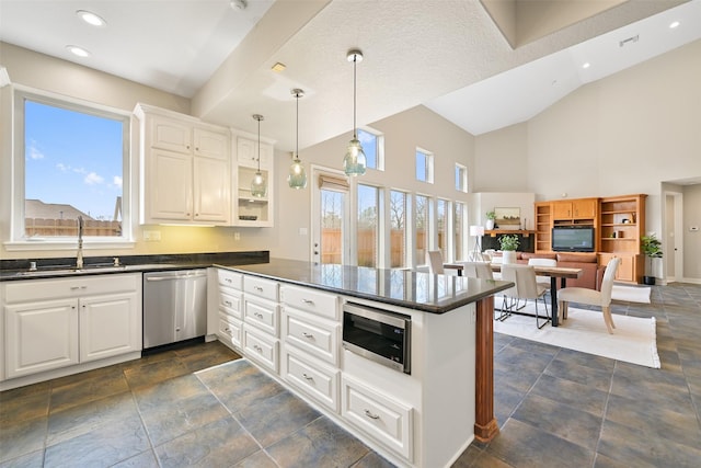 kitchen featuring dark countertops, appliances with stainless steel finishes, a peninsula, white cabinets, and a sink