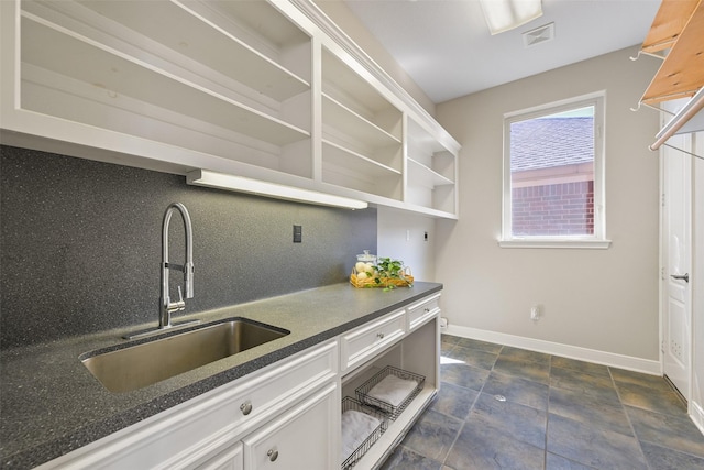 kitchen featuring visible vents, a sink, baseboards, decorative backsplash, and open shelves