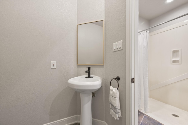 full bathroom with a shower with curtain and a textured wall