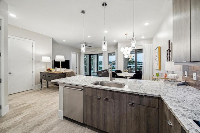 kitchen with dark brown cabinetry, light stone counters, decorative light fixtures, a sink, and stainless steel dishwasher