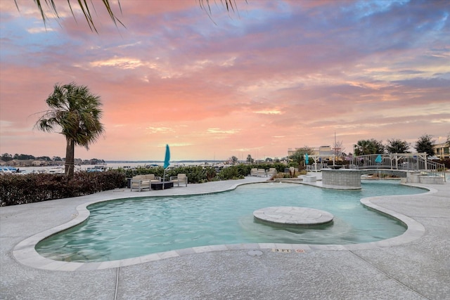 pool at dusk featuring a patio area and an outdoor pool