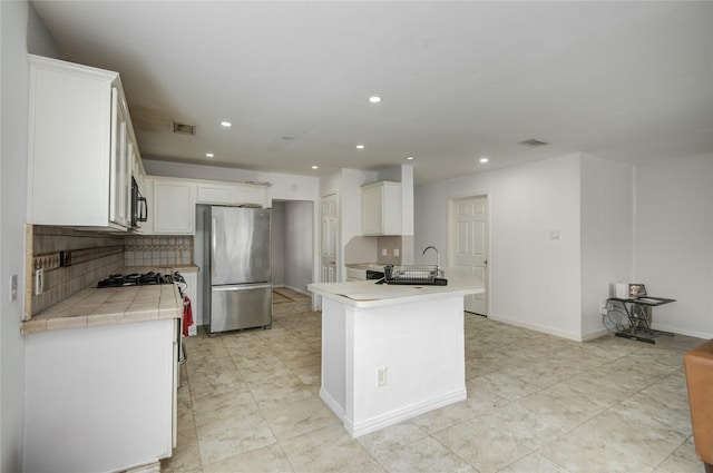 kitchen featuring visible vents, white cabinetry, stainless steel appliances, and a sink