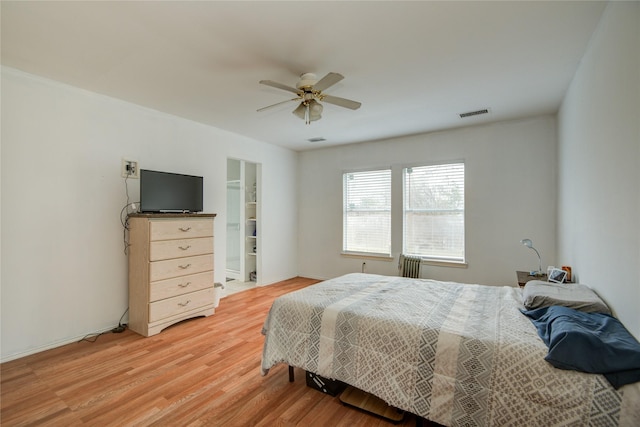 bedroom featuring a ceiling fan, visible vents, radiator heating unit, and wood finished floors