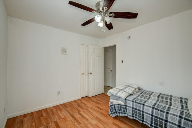 bedroom with light wood-style floors, baseboards, and a ceiling fan