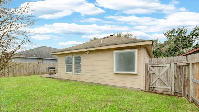 rear view of house with a gate, fence, and a lawn