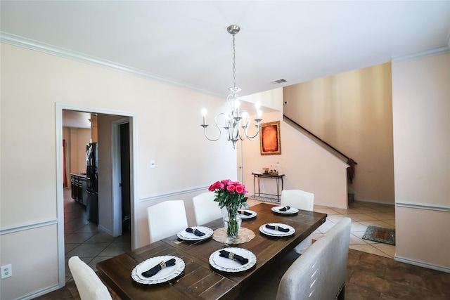 dining area featuring ornamental molding, dark tile patterned floors, visible vents, and a notable chandelier