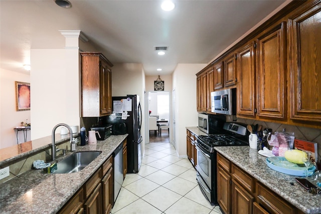 kitchen featuring stone counters, visible vents, stainless steel appliances, and a sink