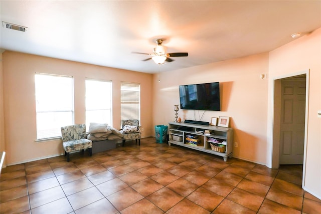 living area featuring ceiling fan, visible vents, baseboards, and dark tile patterned flooring