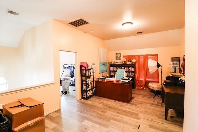 office area featuring vaulted ceiling, light wood-type flooring, and visible vents