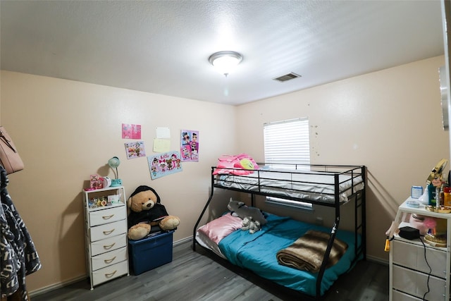 bedroom with a textured ceiling, dark wood finished floors, visible vents, and baseboards