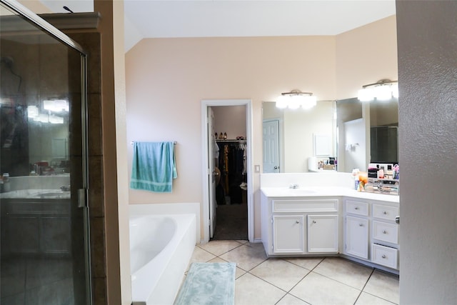 bathroom featuring tile patterned floors, a garden tub, a spacious closet, vaulted ceiling, and vanity