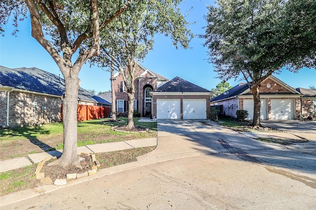 traditional-style house featuring a garage, brick siding, fence, and driveway