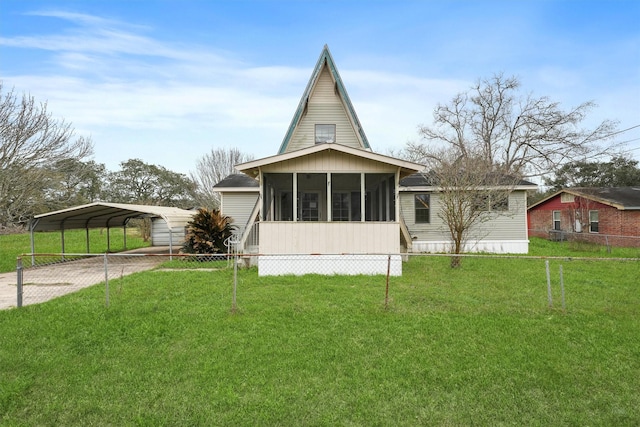 rear view of property featuring a carport, driveway, a lawn, and a sunroom