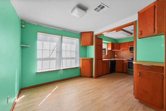 kitchen with stainless steel appliances, light countertops, visible vents, and light wood finished floors