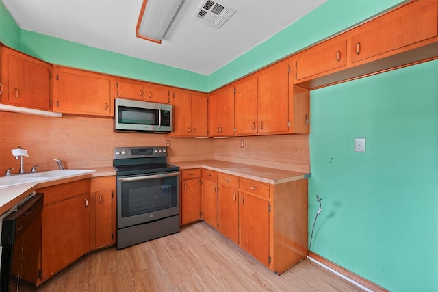 kitchen featuring appliances with stainless steel finishes, light wood-type flooring, light countertops, and visible vents