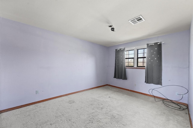 carpeted spare room featuring visible vents and baseboards