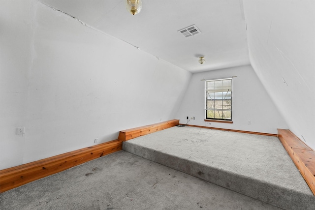 additional living space with carpet floors, visible vents, and vaulted ceiling