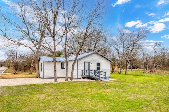 view of front of house featuring metal roof and a front yard