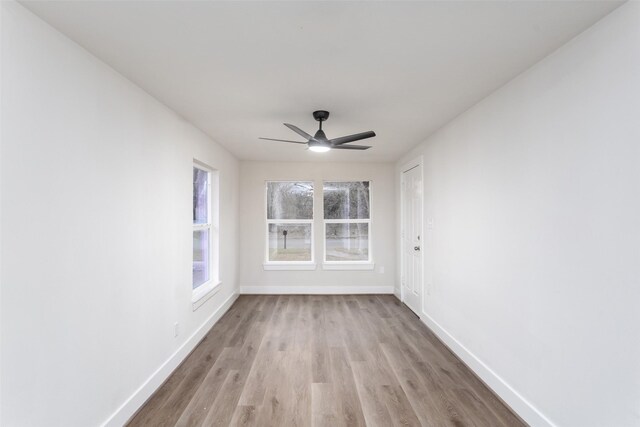 unfurnished room featuring ceiling fan, light wood finished floors, and baseboards