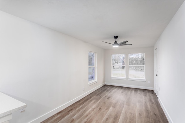 unfurnished room with light wood-style floors, ceiling fan, and baseboards