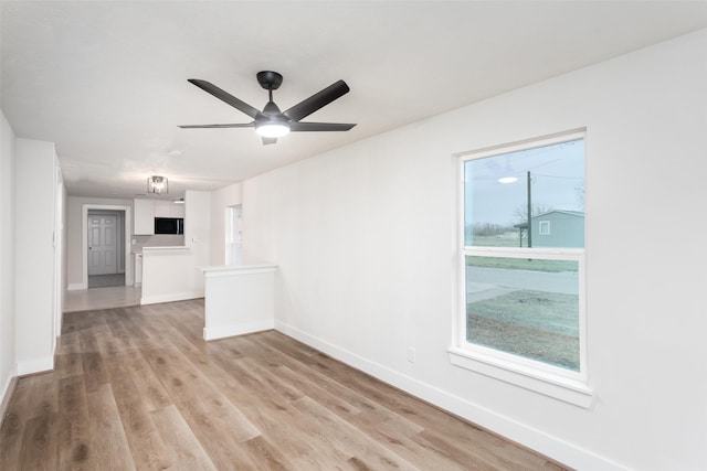 empty room with a ceiling fan, baseboards, and light wood finished floors