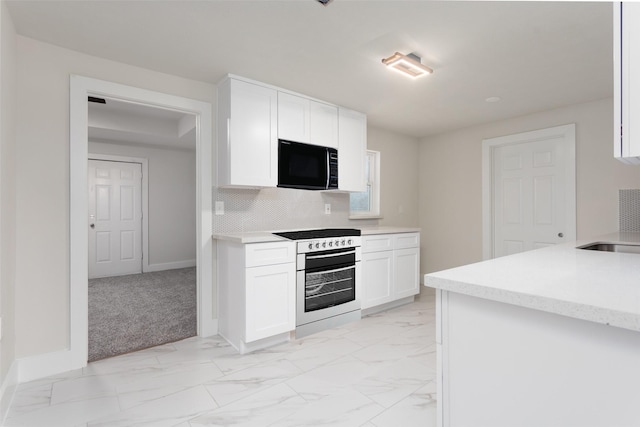 kitchen featuring white cabinets, stove, marble finish floor, light countertops, and black microwave