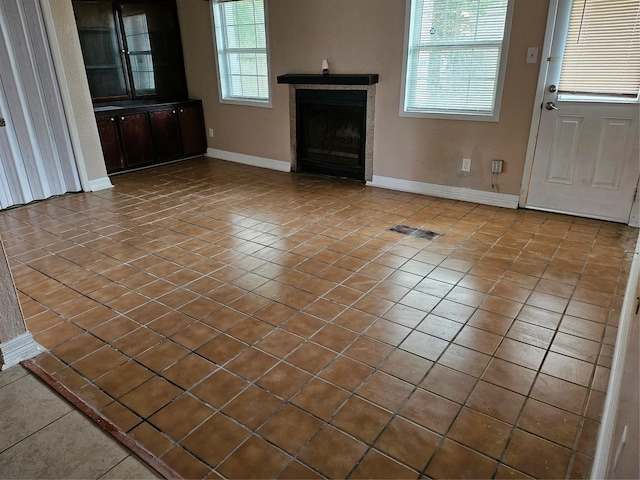 unfurnished living room featuring visible vents, a fireplace, baseboards, and tile patterned floors