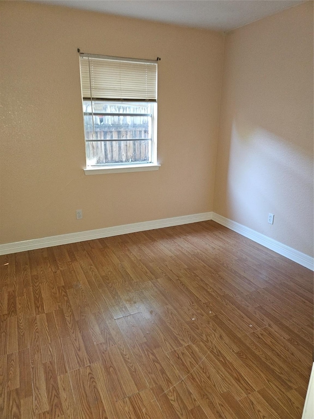 spare room featuring baseboards and wood finished floors