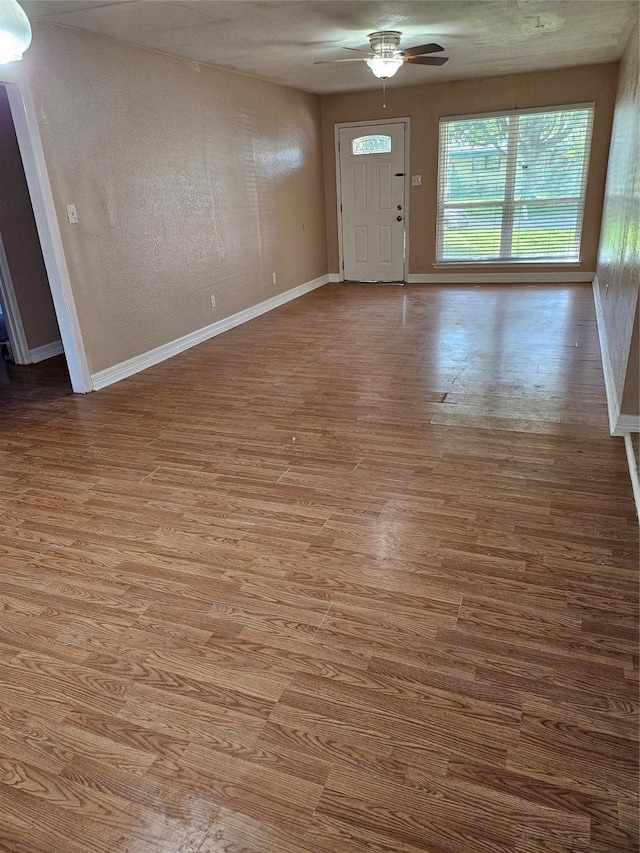 foyer with wood finished floors, a ceiling fan, and baseboards