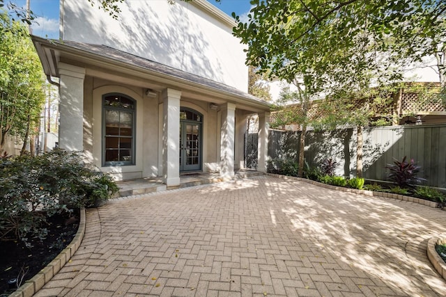 entrance to property featuring fence and stucco siding