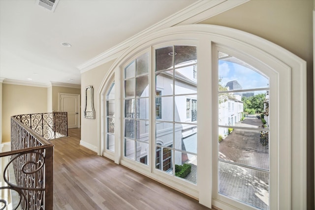 doorway with recessed lighting, wood finished floors, visible vents, baseboards, and crown molding