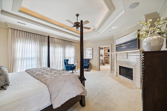 bedroom featuring light colored carpet, a fireplace, baseboards, ornamental molding, and a raised ceiling