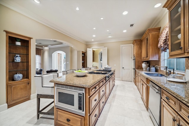 kitchen with arched walkways, stainless steel appliances, visible vents, glass insert cabinets, and a sink