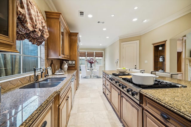 kitchen with light stone counters, stainless steel gas cooktop, visible vents, and a sink