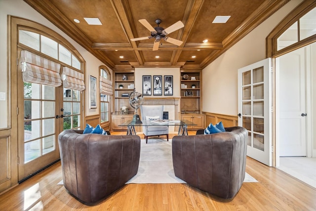 living area featuring coffered ceiling, built in features, french doors, ornamental molding, and light wood finished floors