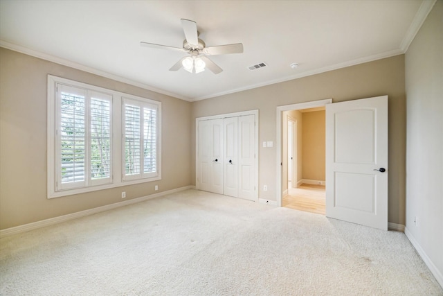 unfurnished bedroom featuring light colored carpet, visible vents, baseboards, ornamental molding, and a closet