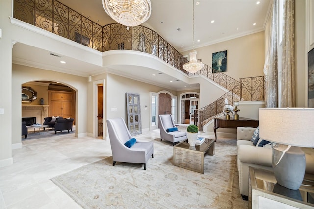 living area with crown molding, arched walkways, a fireplace, and an inviting chandelier