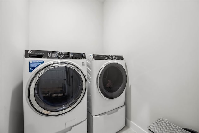 washroom with laundry area, baseboards, and washer and clothes dryer