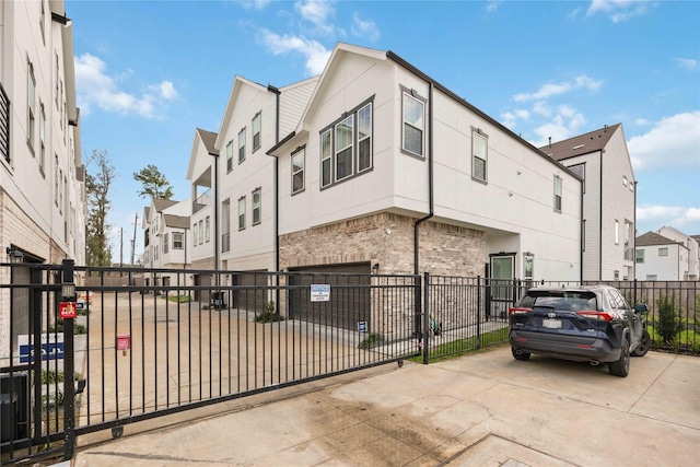 exterior space featuring stucco siding, a residential view, fence, and brick siding