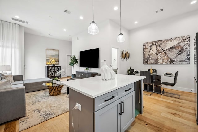 kitchen with light wood finished floors, pendant lighting, light countertops, and open floor plan