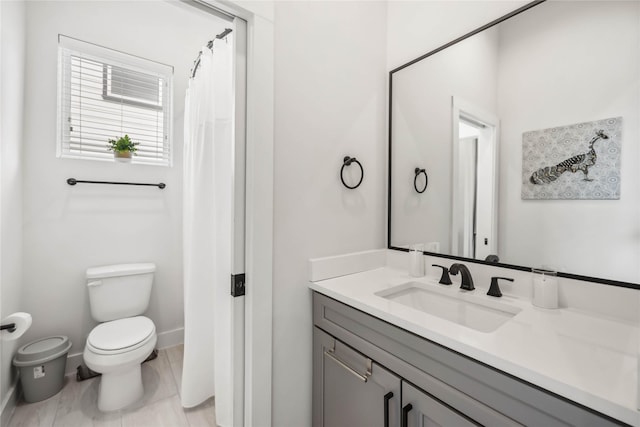 bathroom with toilet, baseboards, and vanity