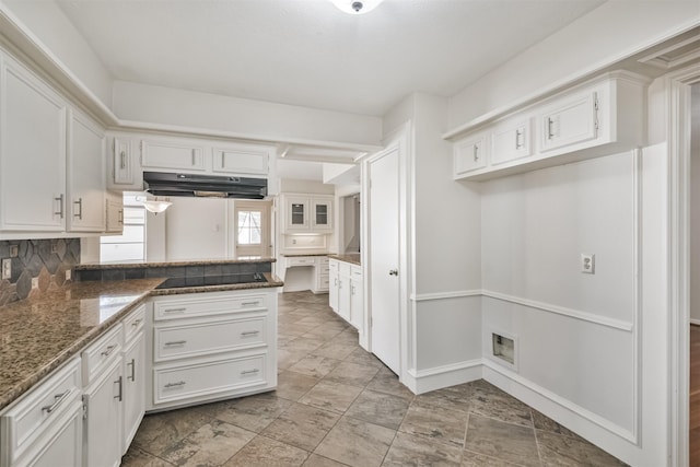 kitchen with under cabinet range hood, black electric cooktop, white cabinets, and dark stone countertops