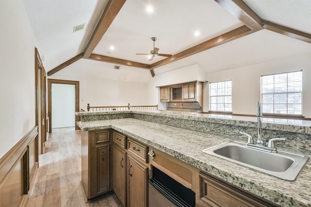 kitchen with visible vents, brown cabinetry, light wood-style flooring, a sink, and beam ceiling