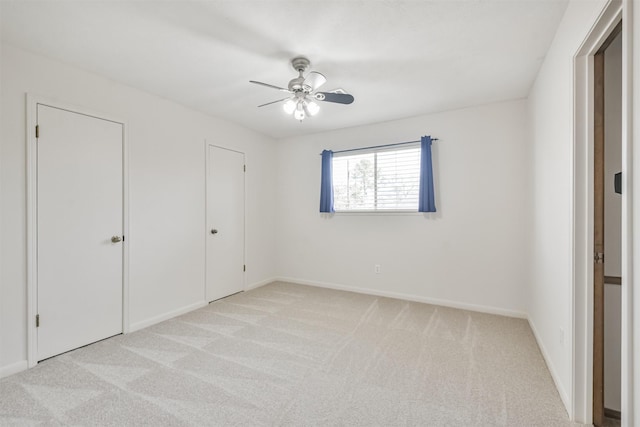 unfurnished bedroom with a ceiling fan, light carpet, and baseboards