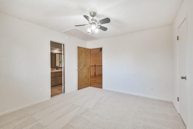 unfurnished bedroom with ensuite bathroom, attic access, a ceiling fan, light carpet, and baseboards