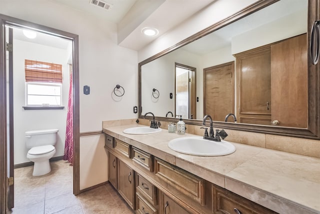 bathroom with visible vents, a sink, toilet, and double vanity