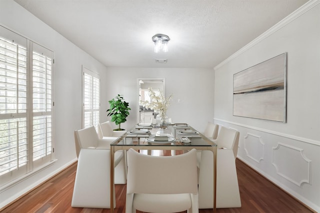 dining area featuring a textured ceiling, visible vents, baseboards, dark wood finished floors, and crown molding